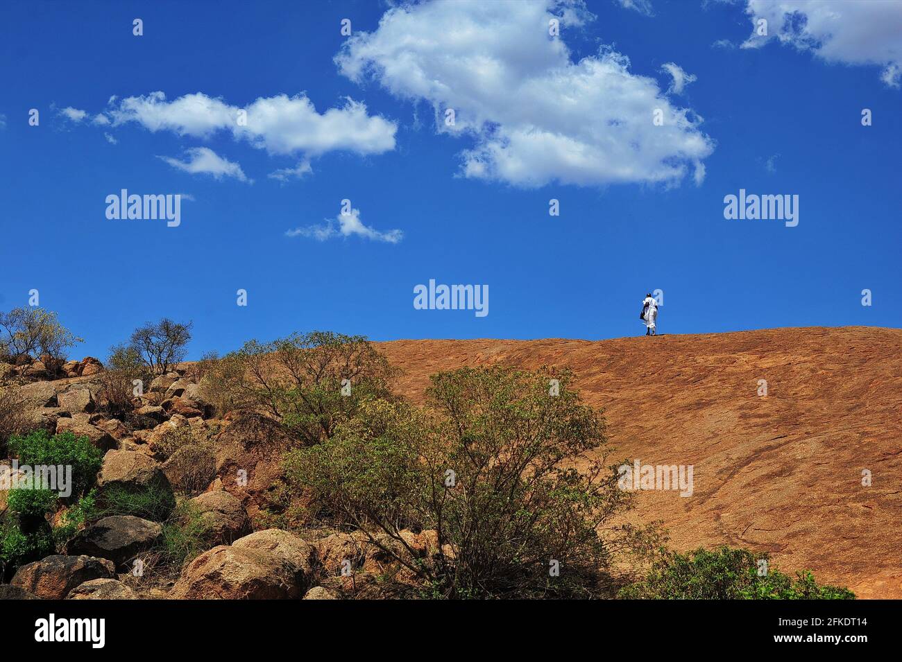 Afrikanische Gläubige, die in Limpopo, Südafrika, einen felsigen Hügel hinaufgehen, um an einem klaren Tag mit blauem Himmel zu beten Stockfoto