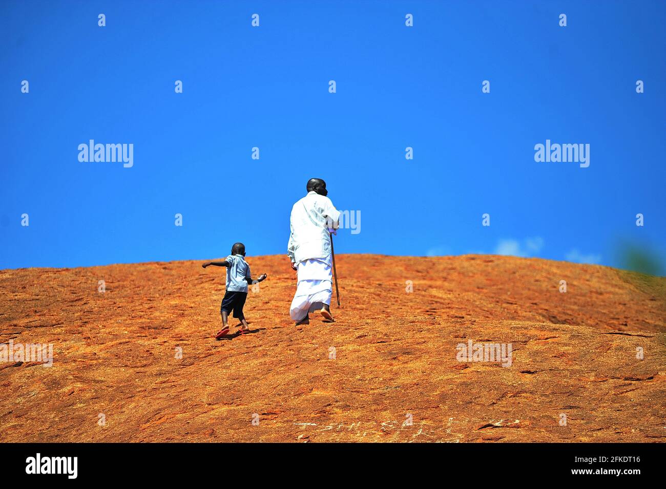 Afrikanische Gläubige, die in Limpopo, Südafrika, einen felsigen Hügel hinaufgehen, um an einem klaren Tag mit blauem Himmel zu beten Stockfoto