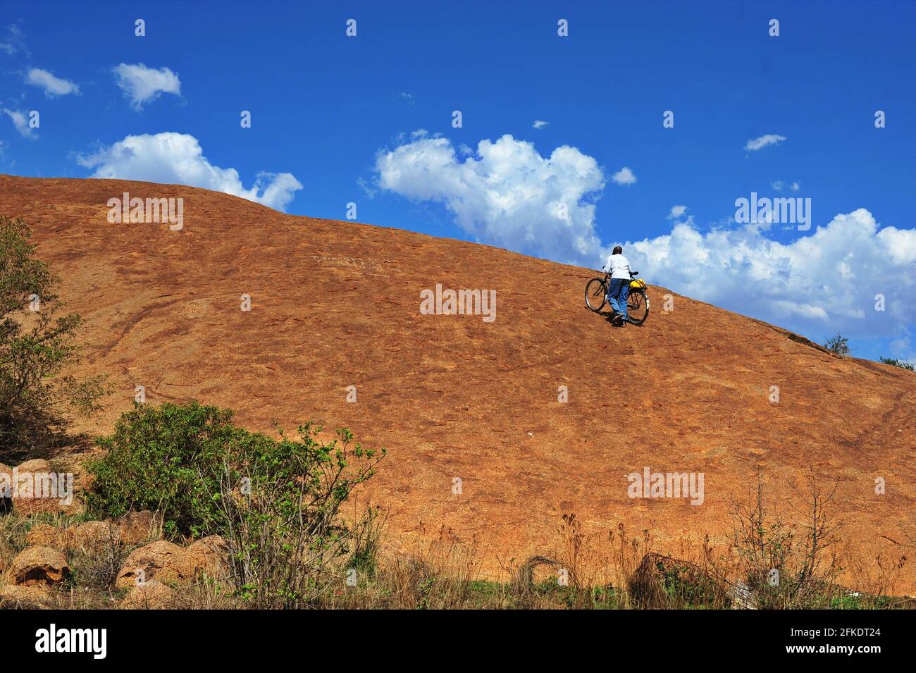 Afrikanische Gläubige, die in Limpopo, Südafrika, einen felsigen Hügel hinaufgehen, um an einem klaren Tag mit blauem Himmel zu beten Stockfoto