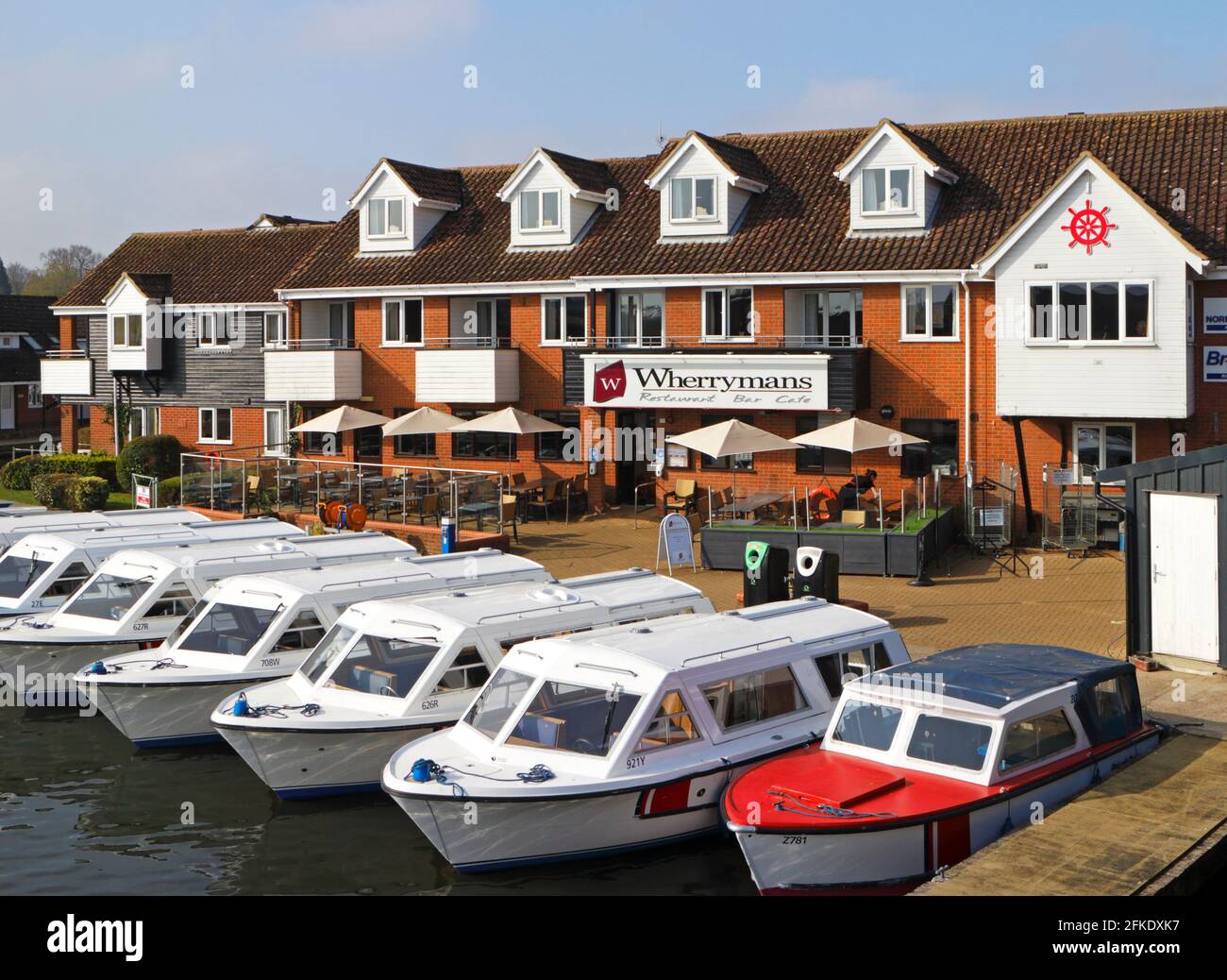 Das Wherrymans Restaurant und Café mit Sitzplätzen im Freien und Tagesausleihbooten, die an der Brücke auf dem Fluss Bure in Wroxham, Norfolk, England, Großbritannien, festgemacht sind. Stockfoto