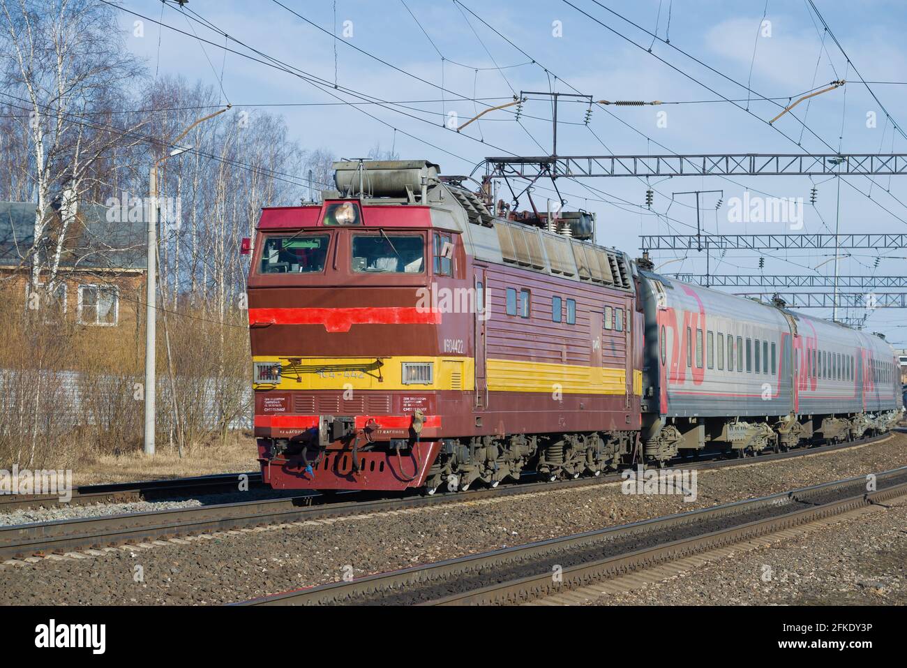 SHARYA, RUSSLAND - 10. APRIL 2021: Tschechische Elektrolokomotive CHS-4T mit Personenzug an einem Aprilnachmittag. Sharya Station der Nordbahn Stockfoto
