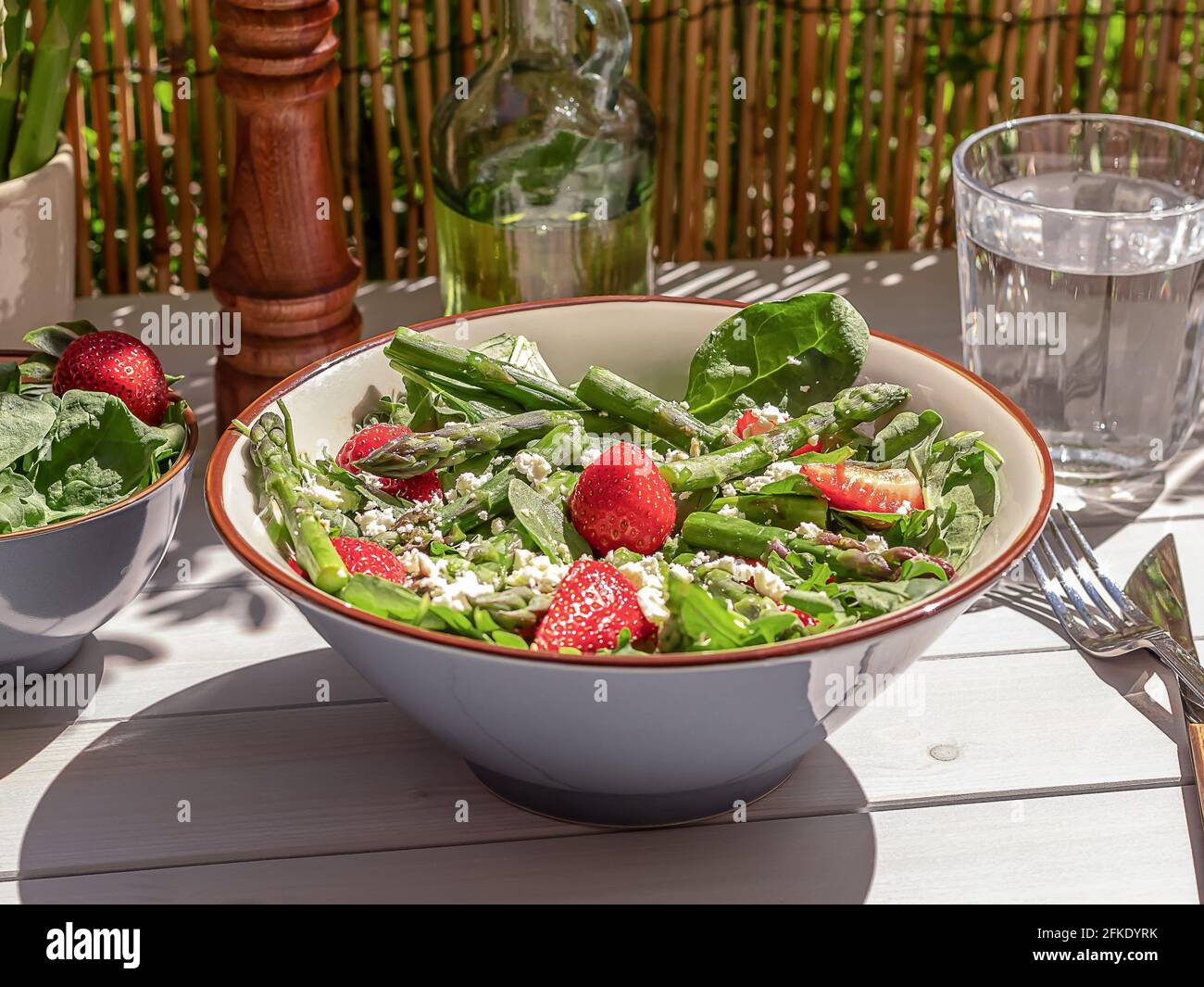 Frische Erdbeeren, grüner Spargel, Feta-Käse, Babyspinat und Rukula-Salat in einer Schüssel mit Mineralwasser serviert. Stockfoto