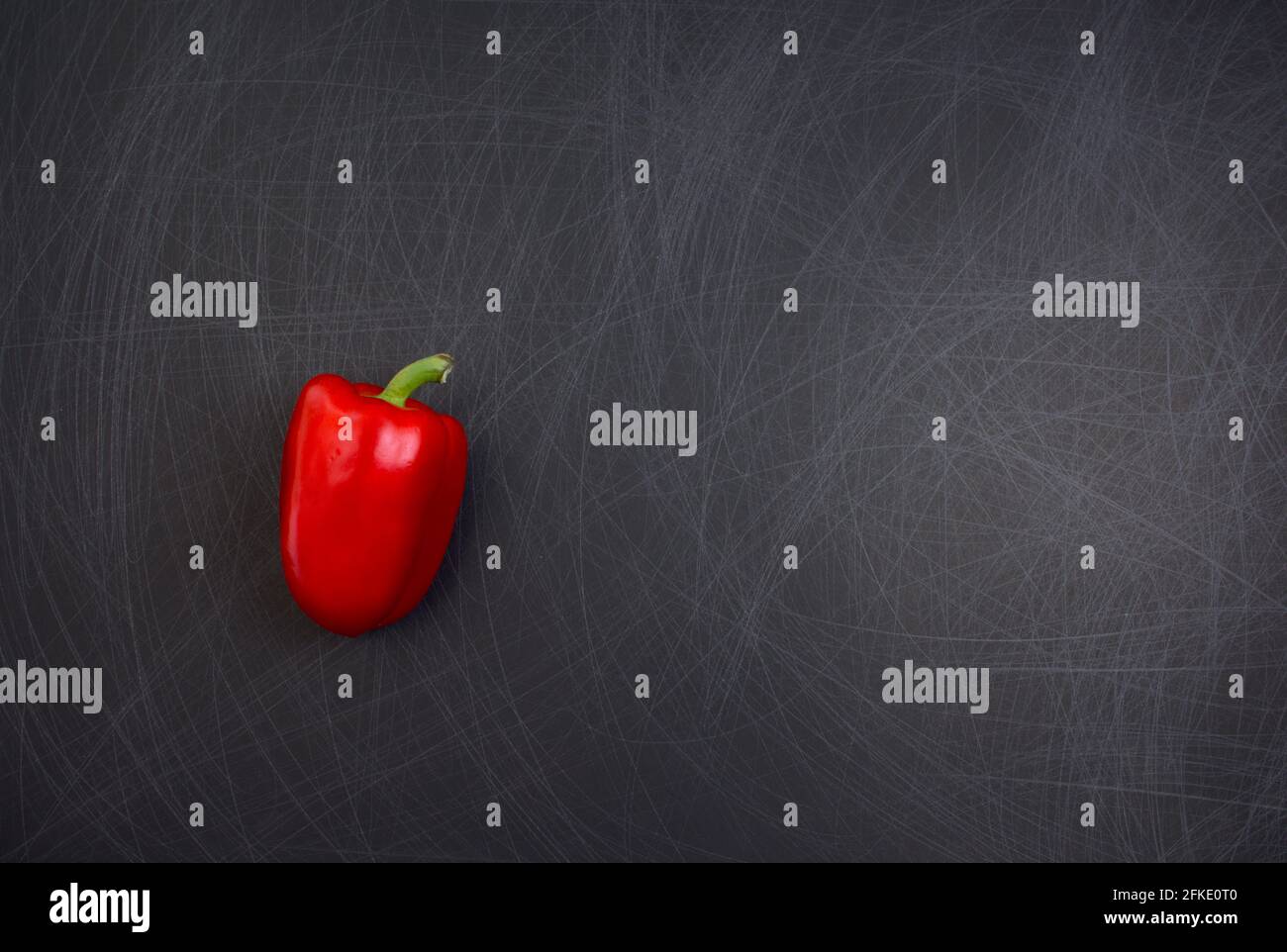 Rote Glocke oder Paprika Gemüse flach lag auf grunge zerkratzt Textur schwarzen Hintergrund. Off-Center mit Kopierplatz, Draufsicht, horizontales Bild. Stockfoto