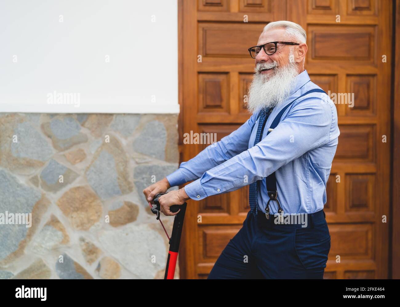 Business Senior Mann gehen, um mit Elektroroller arbeiten - Glücklich Mode männlich Spaß im Freien Stockfoto