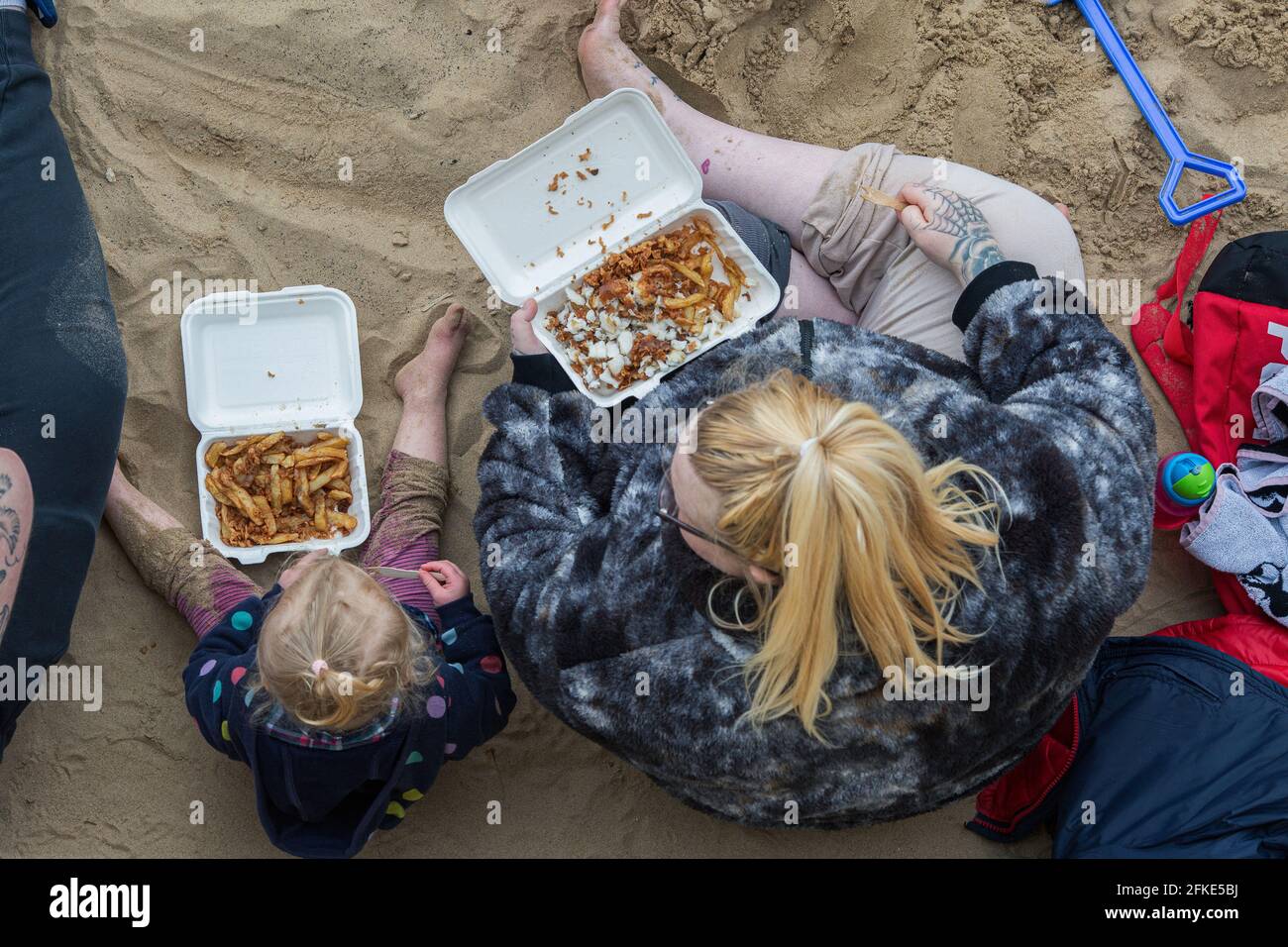 Eine junge Familie isst ihren Fisch und ihre Chips am Hartlepool Headland Beach, England, UK. Familie nehmen Fisch und Chips von lokalen Chippy . Stockfoto