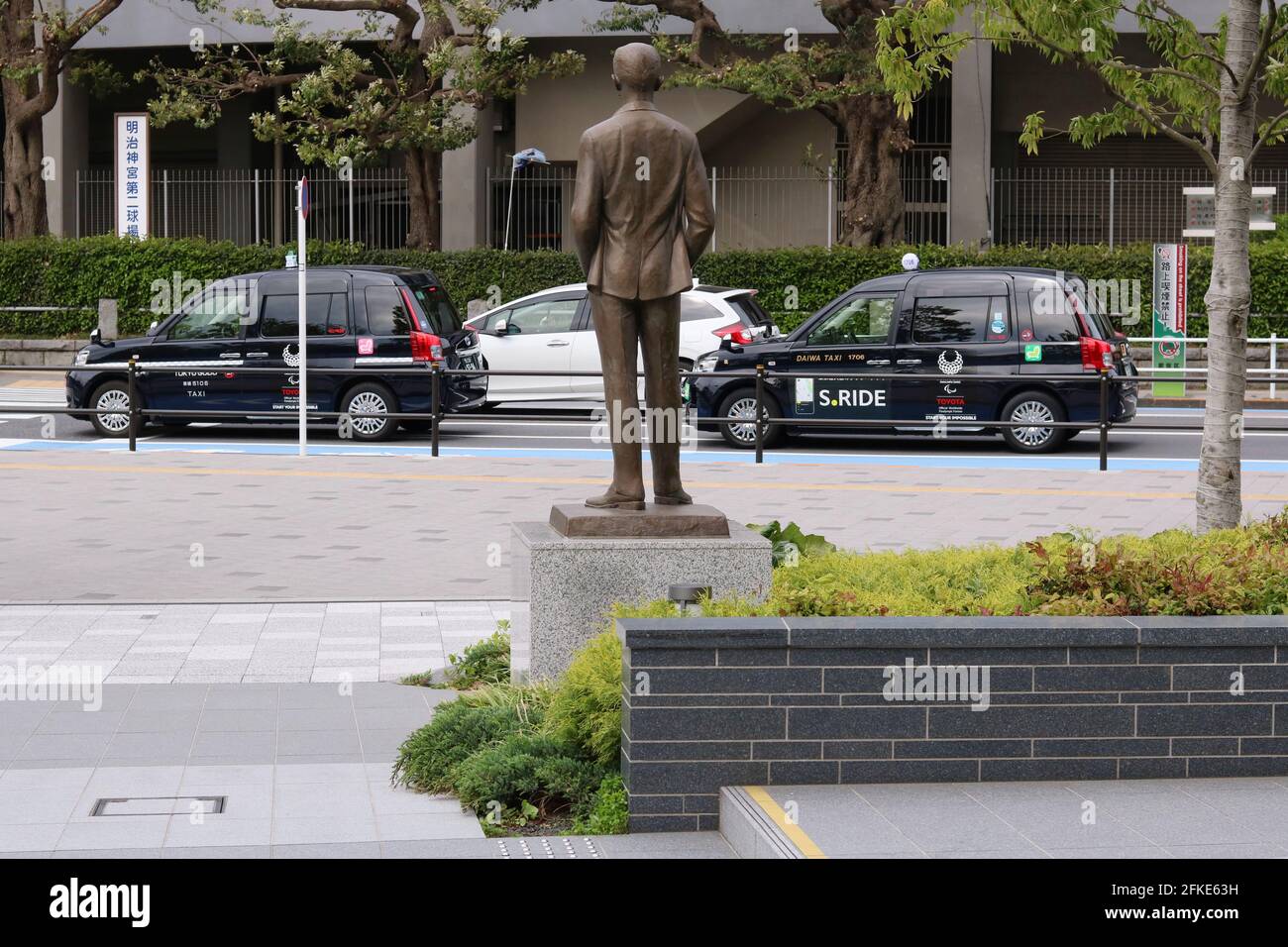 Statue des Olympiagründers Pierre de Coubertin im Japanischen Olympischen Museum. Unterwegs sind Taxis mit den Logos der Paralympischen Spiele von Tokio. (4/2021) Stockfoto