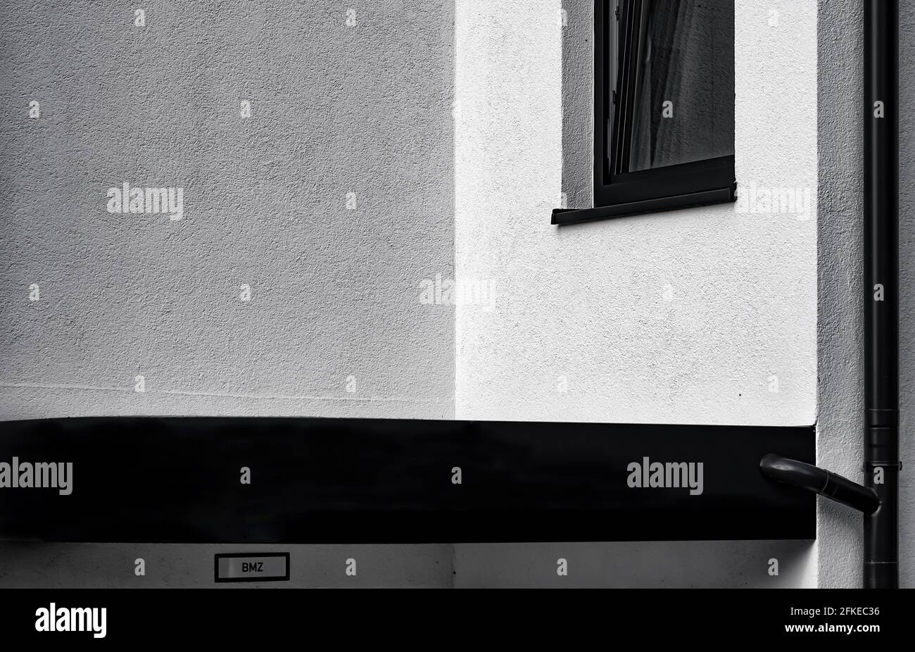 Blick auf das Fenster eines Wohnhauses. Davor eine Wand. Stockfoto