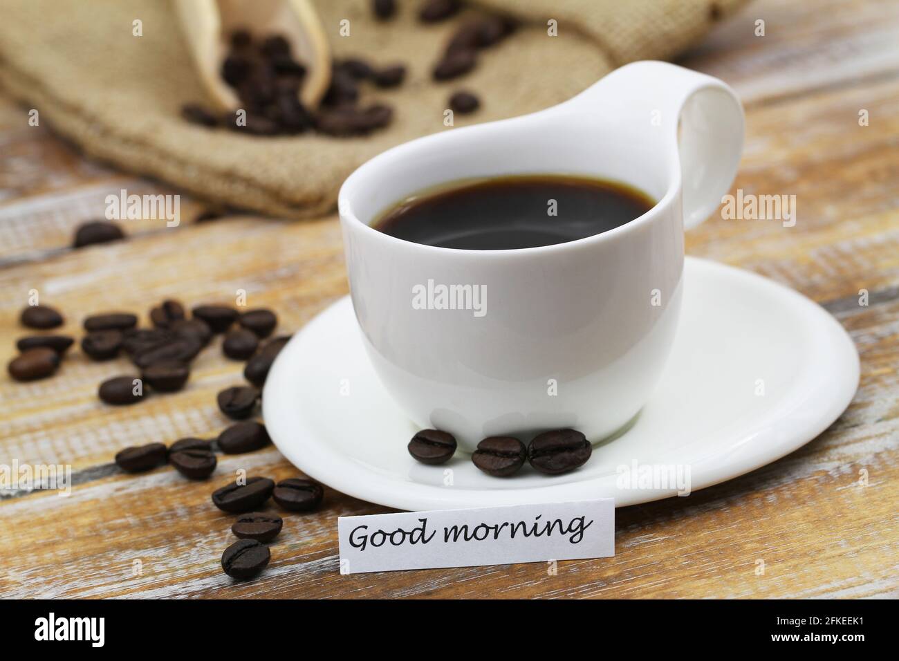 Good Morning Karte mit schwarzem Kaffee in einfacher weißer Tasse Mit Kaffeebohnen verstreut Stockfoto