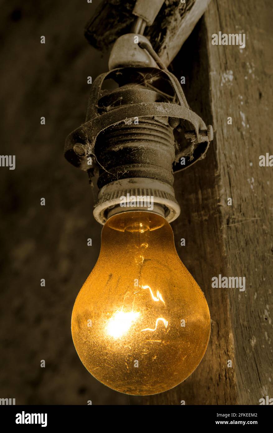 Eine alte Glühbirne, die an einem elektrischen Kabel an einem Strahl hängt  Stockfotografie - Alamy