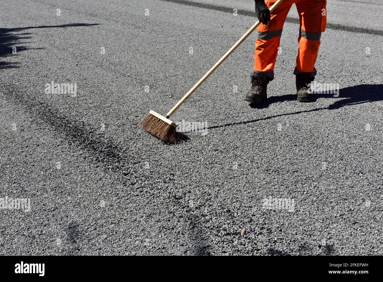 Straßenwartung fegen bis verlieren Späne nach dem Verbreiten von Bitumen und Schottersplitter für die Straßenbelag Stockfoto