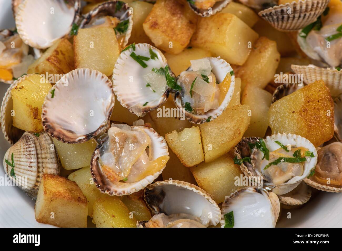 Gedünstete Herzmuscheln mit gebratenen Kartoffeln in der weißen Schale, Mariniere Rezept Stockfoto