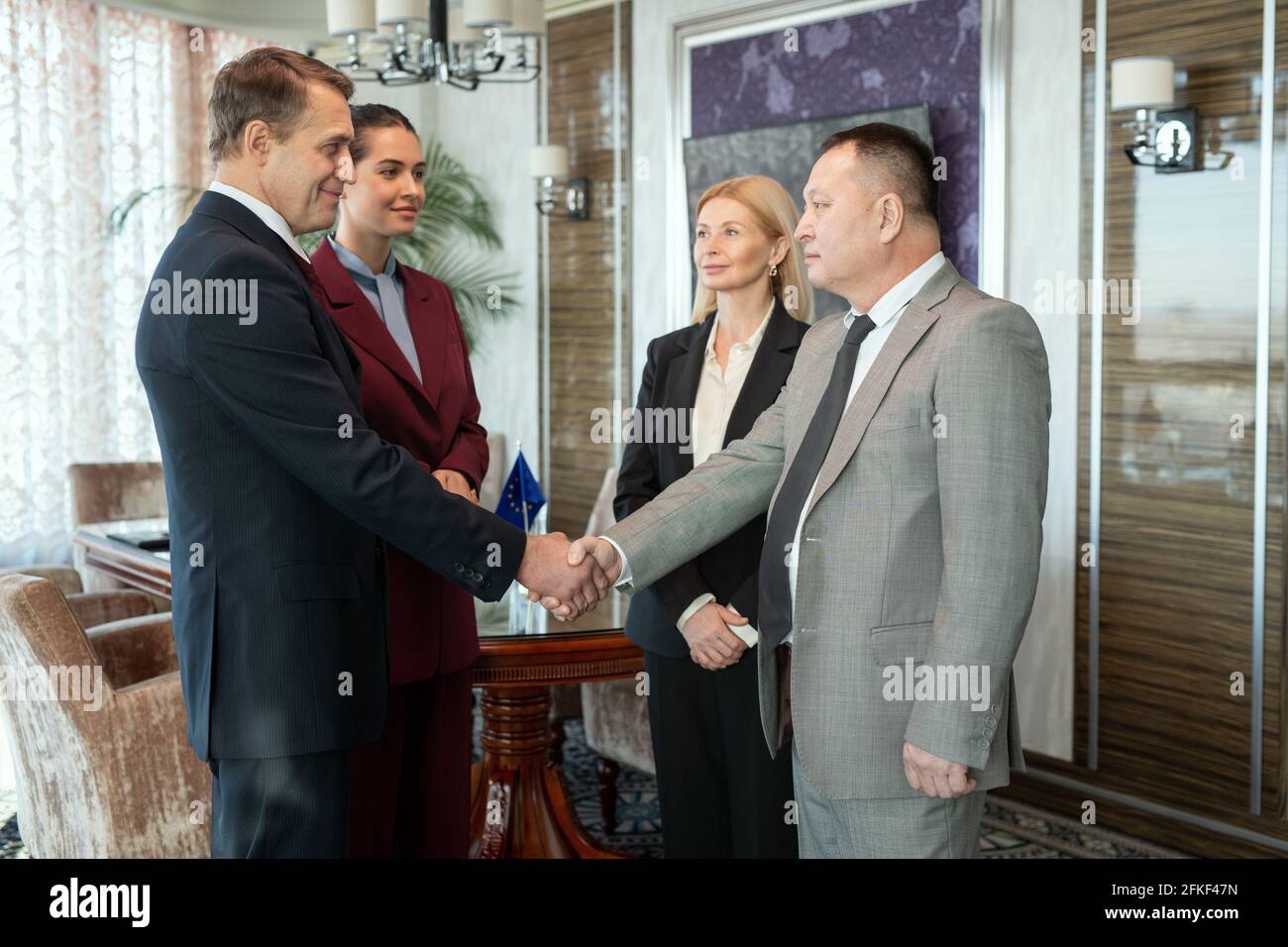 Eine Gruppe erfolgreicher eleganter Geschäftsleute, die sich im Sitzungssaal die Hände schütteln Stockfoto