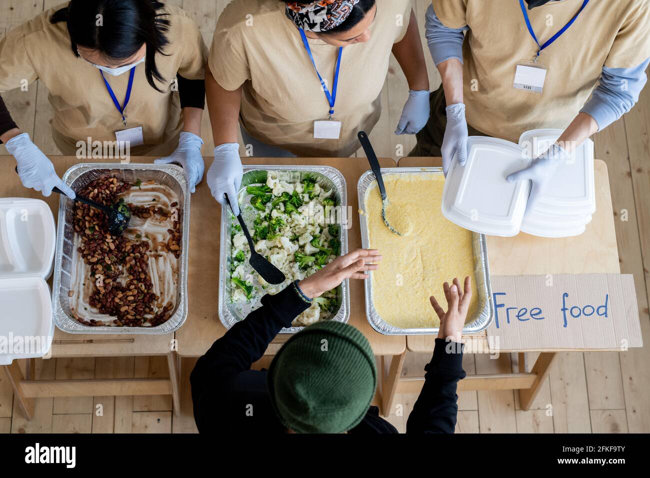 Junge Freiwillige geben den Menschen Behälter mit kostenlosem Essen In Not Stockfoto