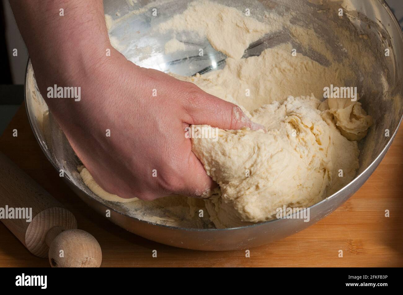 Der Mann knetet den Brotteig auf einem hölzernen Plätzchen Stockfoto