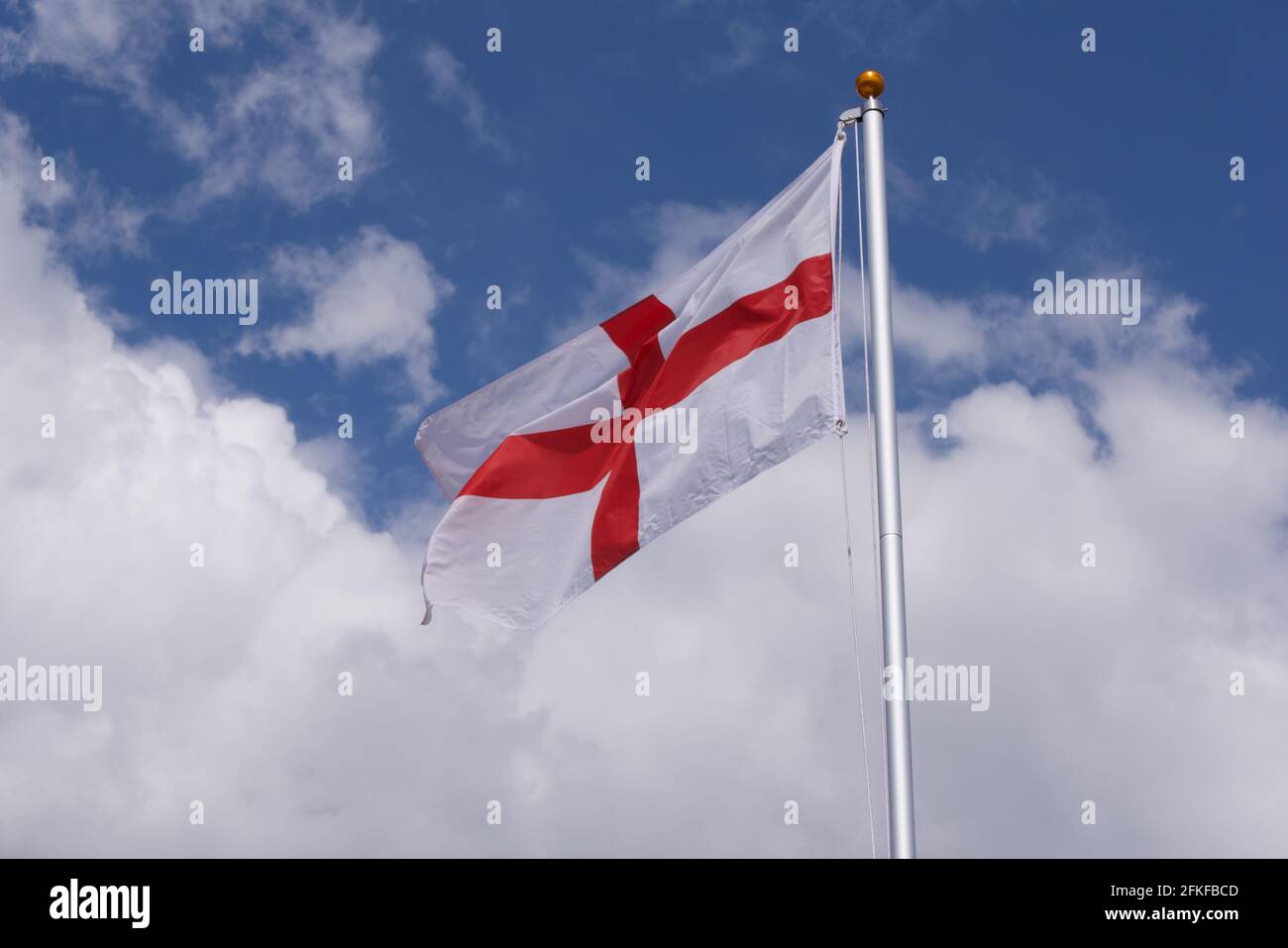 Rote und weiße Flagge von St. George England gegen den blau bewölkten Himmel. Hochwertige Fotos Stockfoto