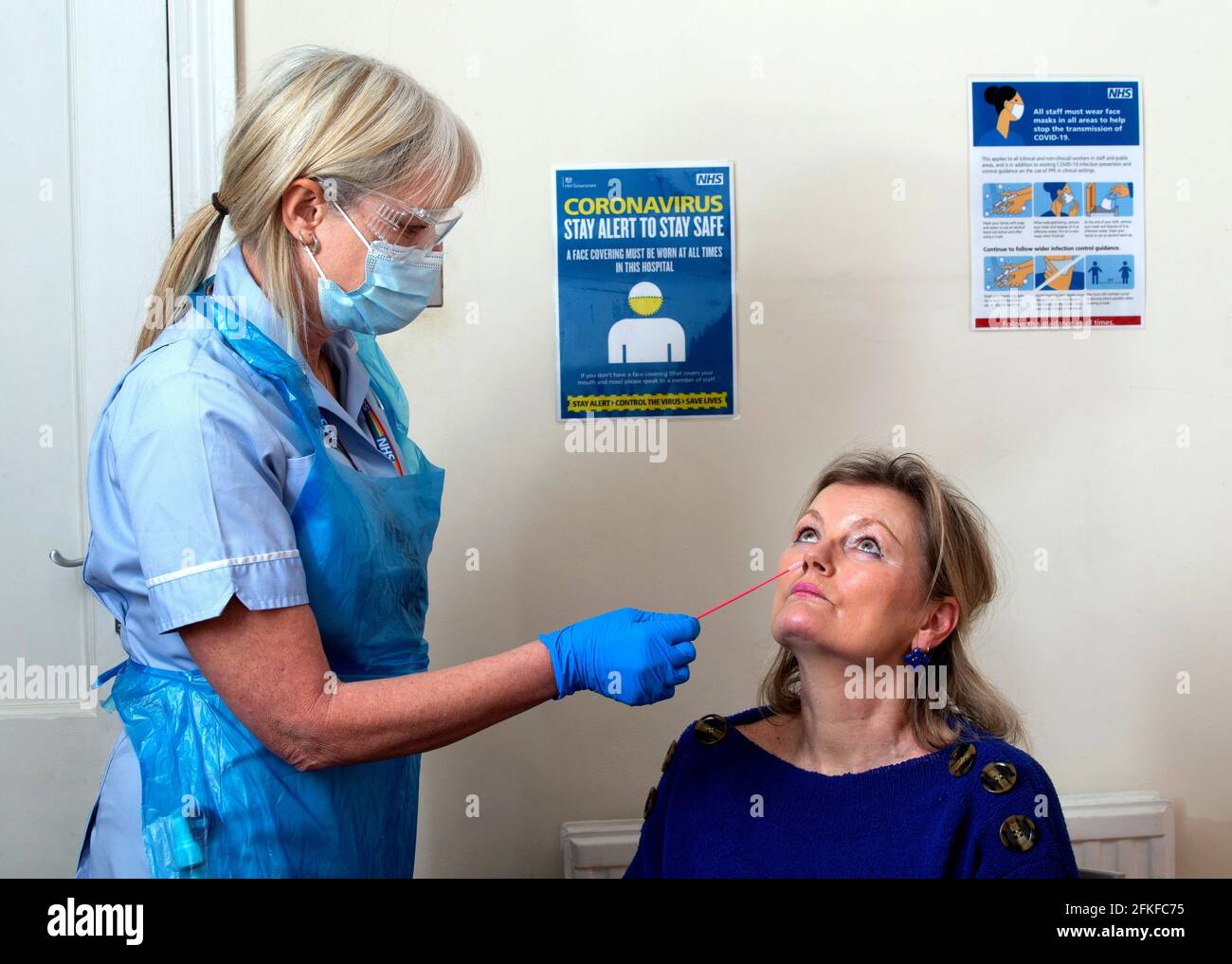 Eine NHS-Krankenschwester führt einen lateralen Flow-Covid-Test für einen Patienten durch. Der Test ergibt in 30 Minuten ein Ergebnis. Ein Tupfer wird genommen und in eine Lösung gegeben. Stockfoto
