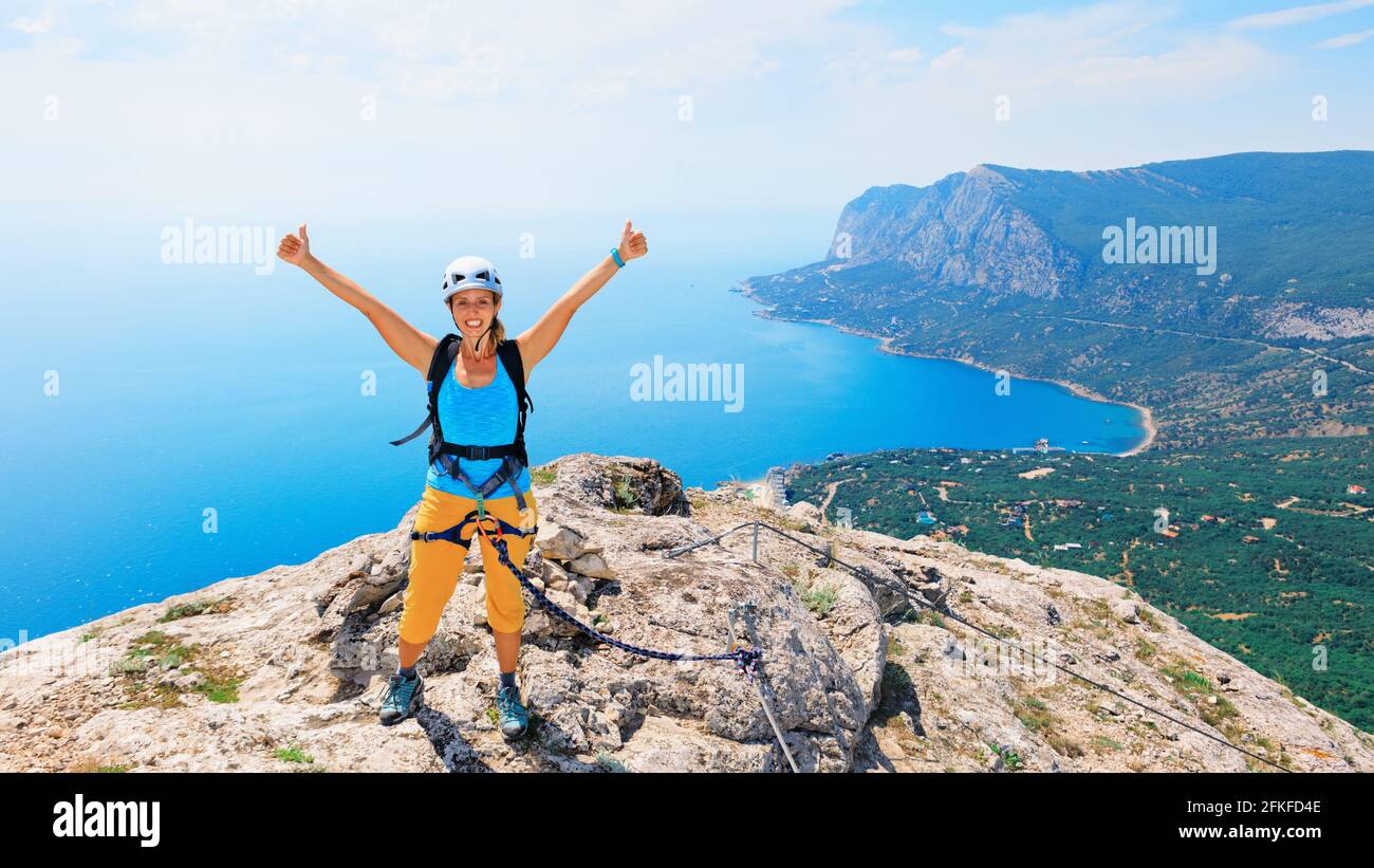 Glückliche junge Frau steht oben auf dem Berg. Atemberaubende Meereslandschaft. Familienreise Abenteuer, Wanderaktivitäten. Klettersteig-Tour mit Kindern, auf der die Natur erkundet wird Stockfoto
