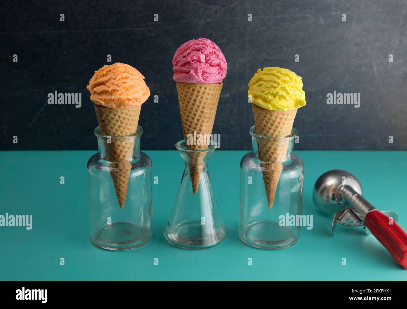 Orange Rosa und Gelbe Kugeln Eis auf einem Tisch Mit Blaugrün Stockfoto