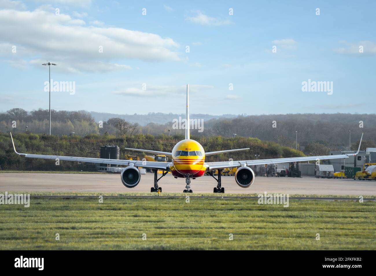 DHL Boeing 737 Düsenflugzeug auf Start- und Landebahn bereit Vom geschäftigen internationalen Verteilungszentrum werden gelb und rot geparkt Stockfoto