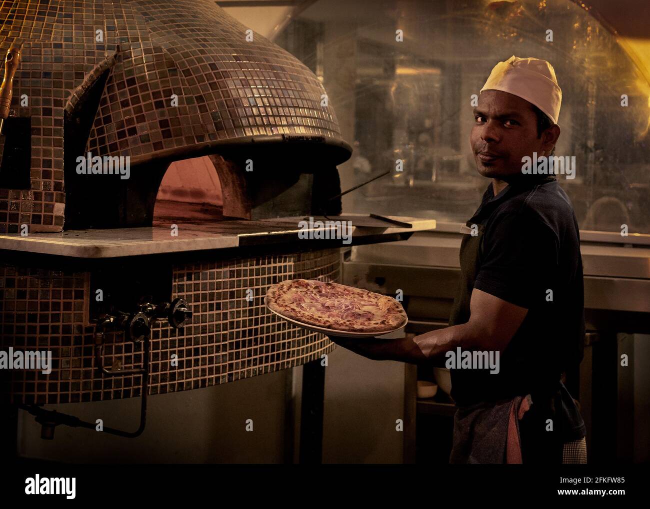 Pizza wurde uns vom Koch mit traditionellem Stein gezeigt Backofen mit heißen Kohlen backen Stockfoto