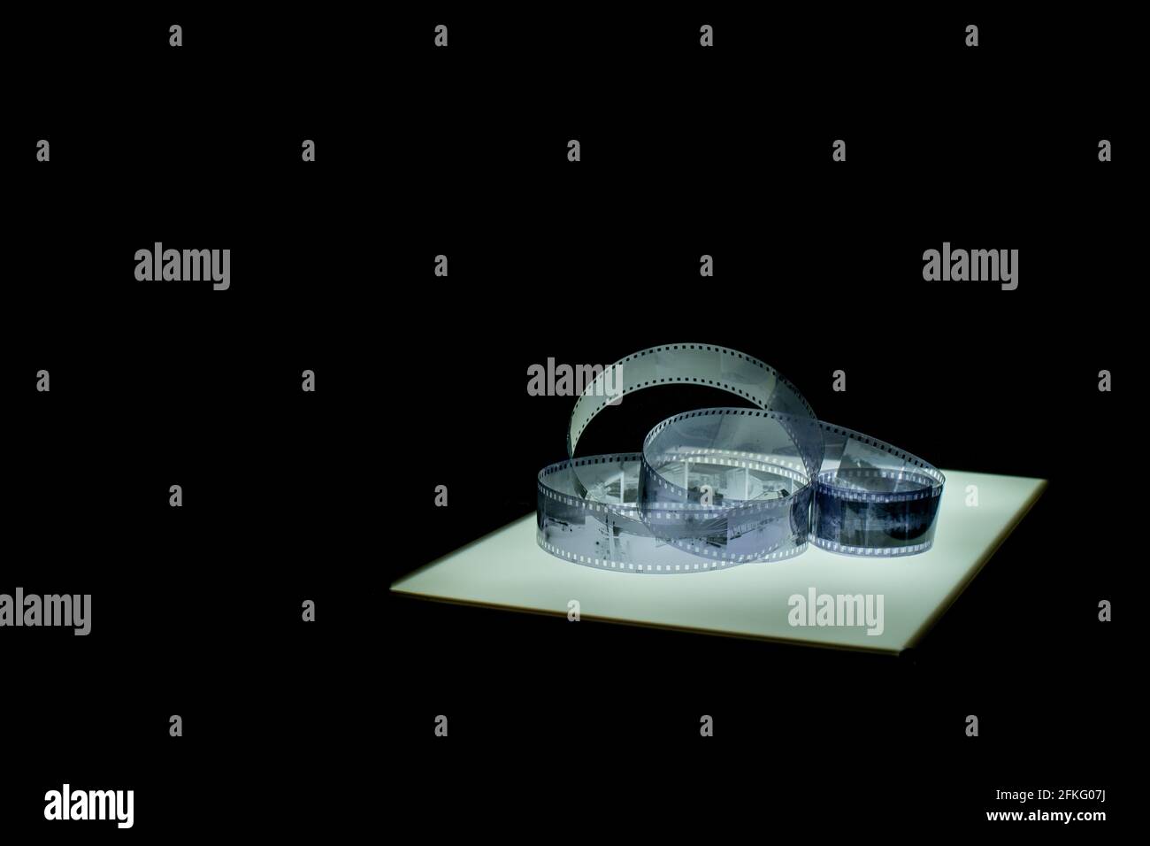 Analoger 35-mm-Negativ-Filmstreifen in Schwarzweiß auf dem Lichttisch, Gesamtansicht mit Kopierfläche, horizontales Format, schwarzer Hintergrund Stockfoto
