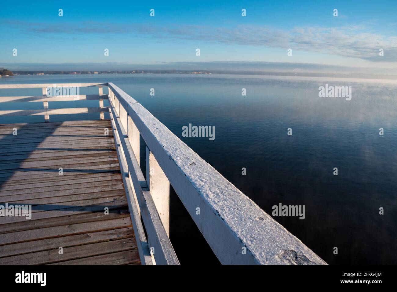 Steg auf einem See mit Nebel. Holzstruktur auf dem Wasser. Sonnenaufgang und Nebel über dem Wasser. Stockfoto