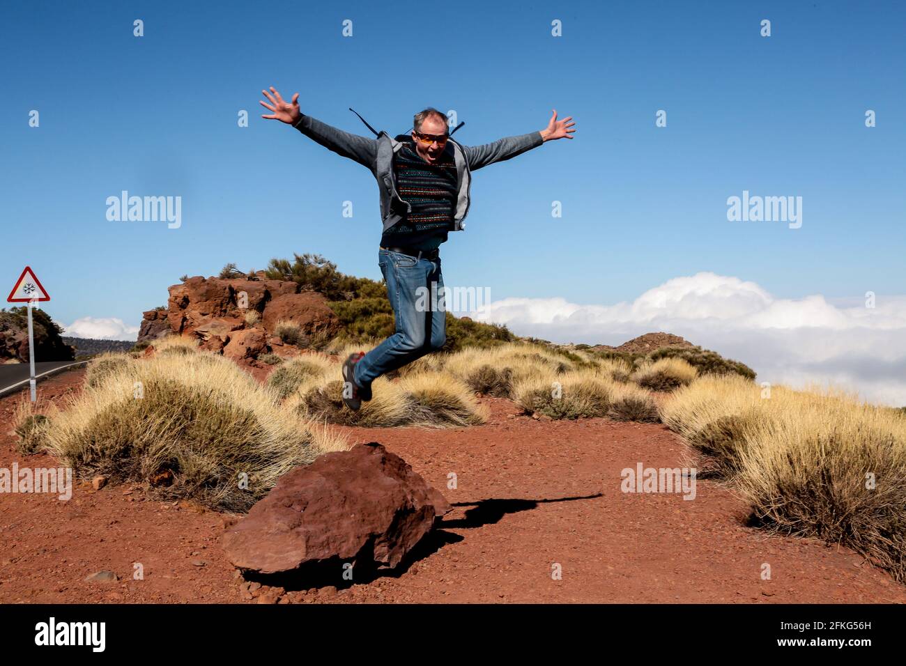 Glücklicher Tourist in vollem Wachstum in einem Sprung. Der Reisende springt vor Freude und macht eine Geste des Sieges. Der Mann kam zur Ruhe auf Teneriffa. Stockfoto