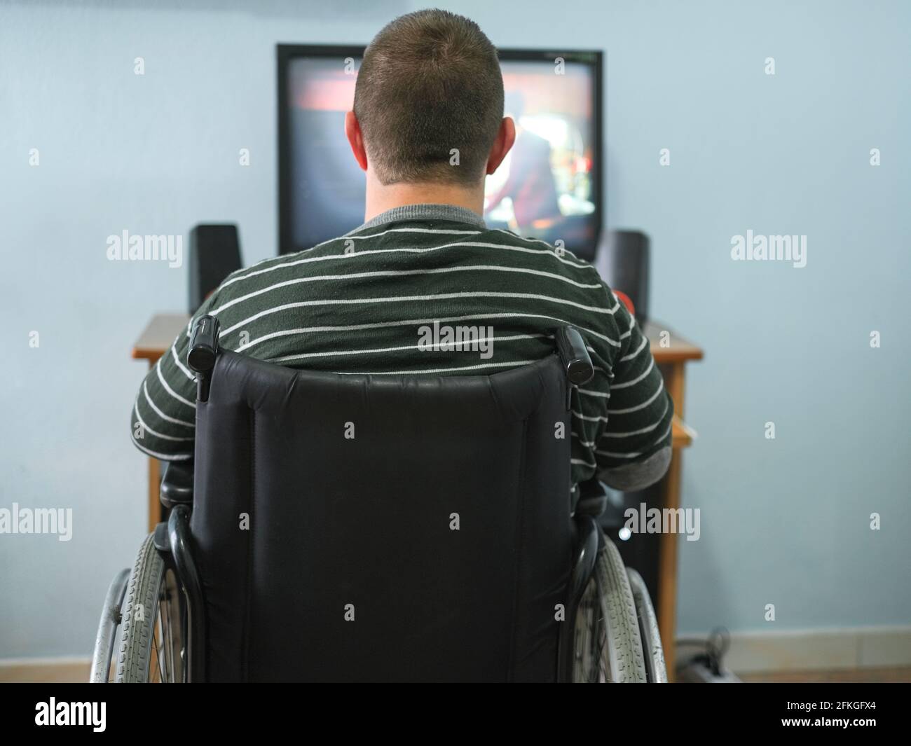 Behinderter Kerl, der sich zu Hause während des Lockdown einen Film am Computer ansieht Zeit, Medizintechnik Stockfoto