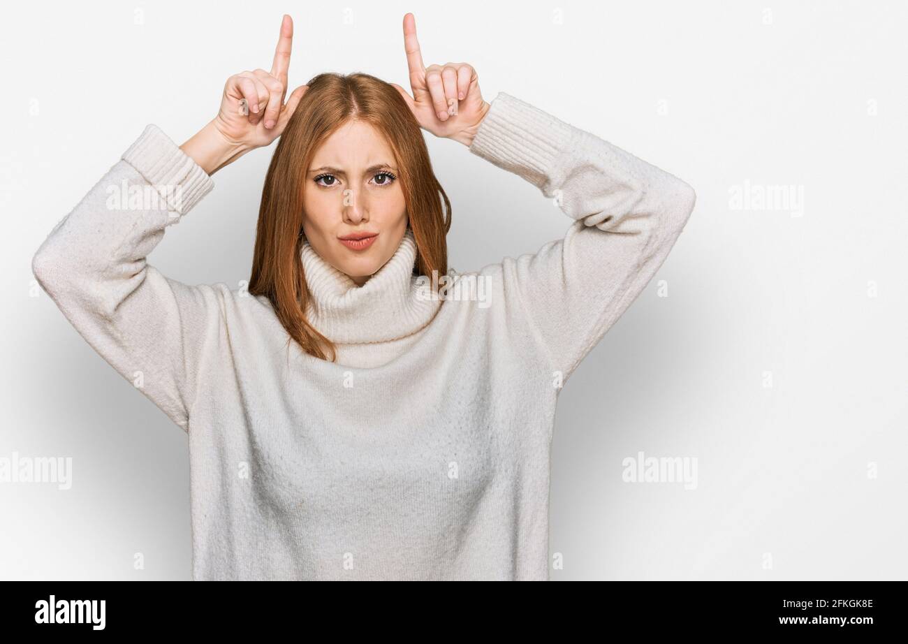 Junge irin trägt legeren Winterpullover und macht lustige Geste Mit Finger über dem Kopf als Stierhörner Stockfoto