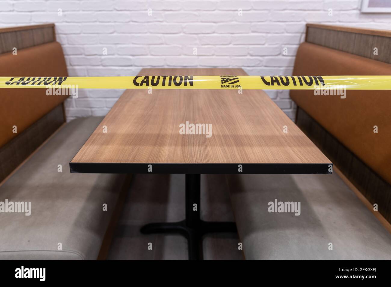 Vorsicht: Gelbes Klebeband auf einem Restauranttisch, der derzeit nur als Entnahmen dient, da die durch die Covid-19-Pandemie verursachten Maßnahmen gesperrt wurden. Stockfoto
