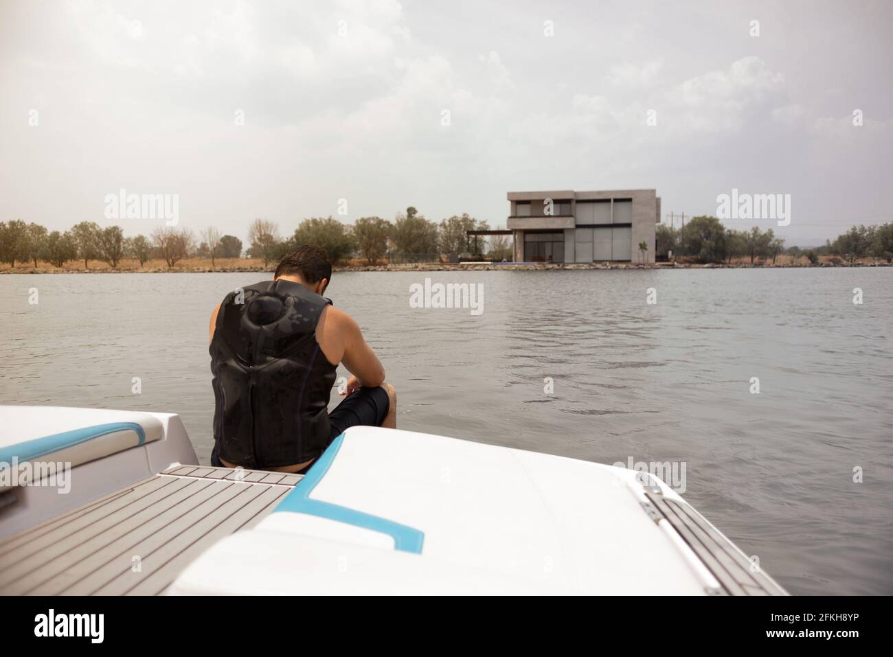 Hispanischer Mann sitzt, ruhig, in einem Boot auf dem See am Mittag Stockfoto