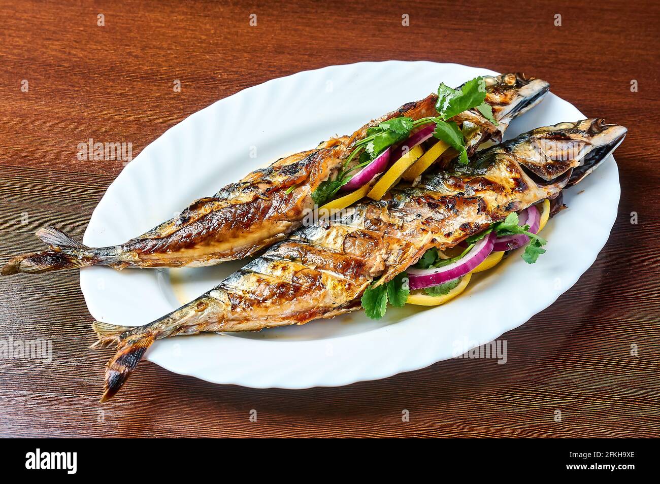 Auf dem Grill gegartes Makrele befindet sich auf einem weißen Teller Stockfoto