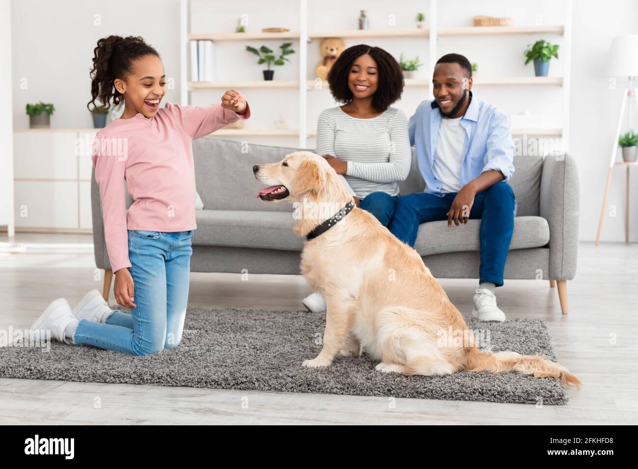 Schwarzes Mädchen trainiert und behandelt ihren gehorsamen Hund Stockfoto