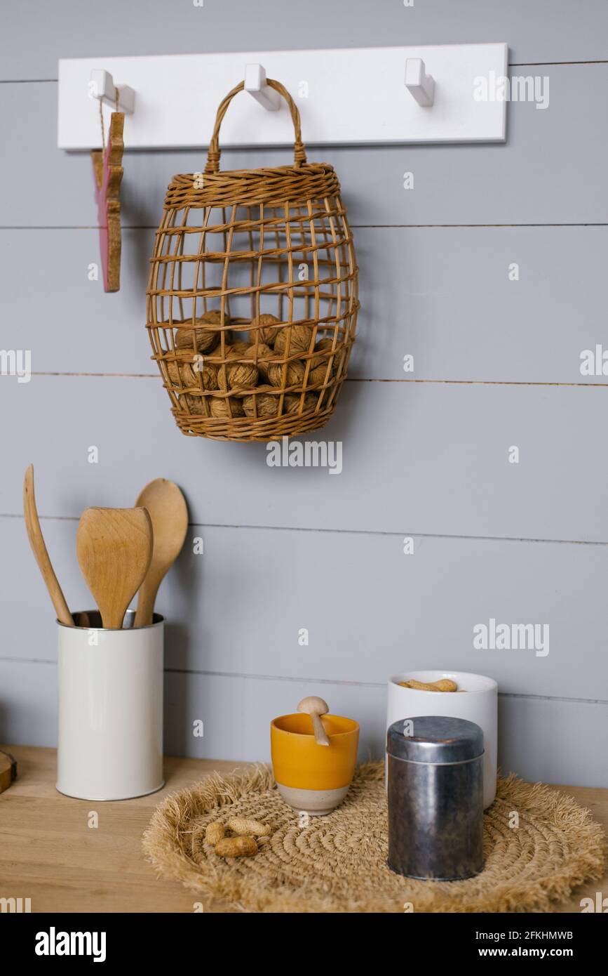 Moderne Kücheneinrichtung mit grauer Holztäfelung im skandinavischen Stil  an der Wand, Walnüssen im Korb, Geschirr und Küchenutensilien  Stockfotografie - Alamy