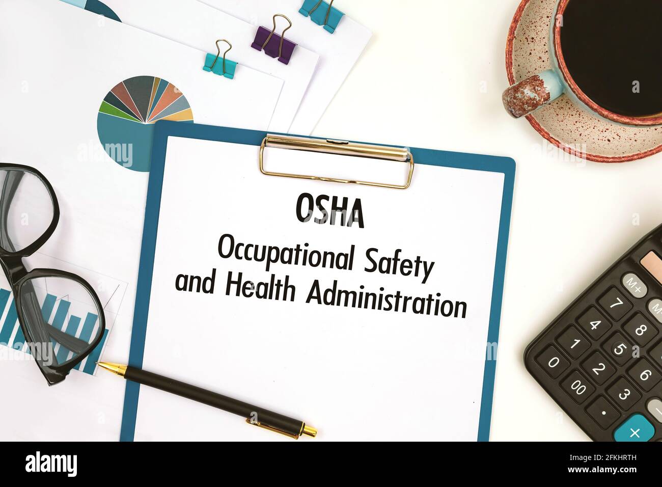 Papier mit Text OSHA - Occupational Safety and Health Administration auf dem Bürotisch, Rechner und Tasse Kaffee Stockfoto