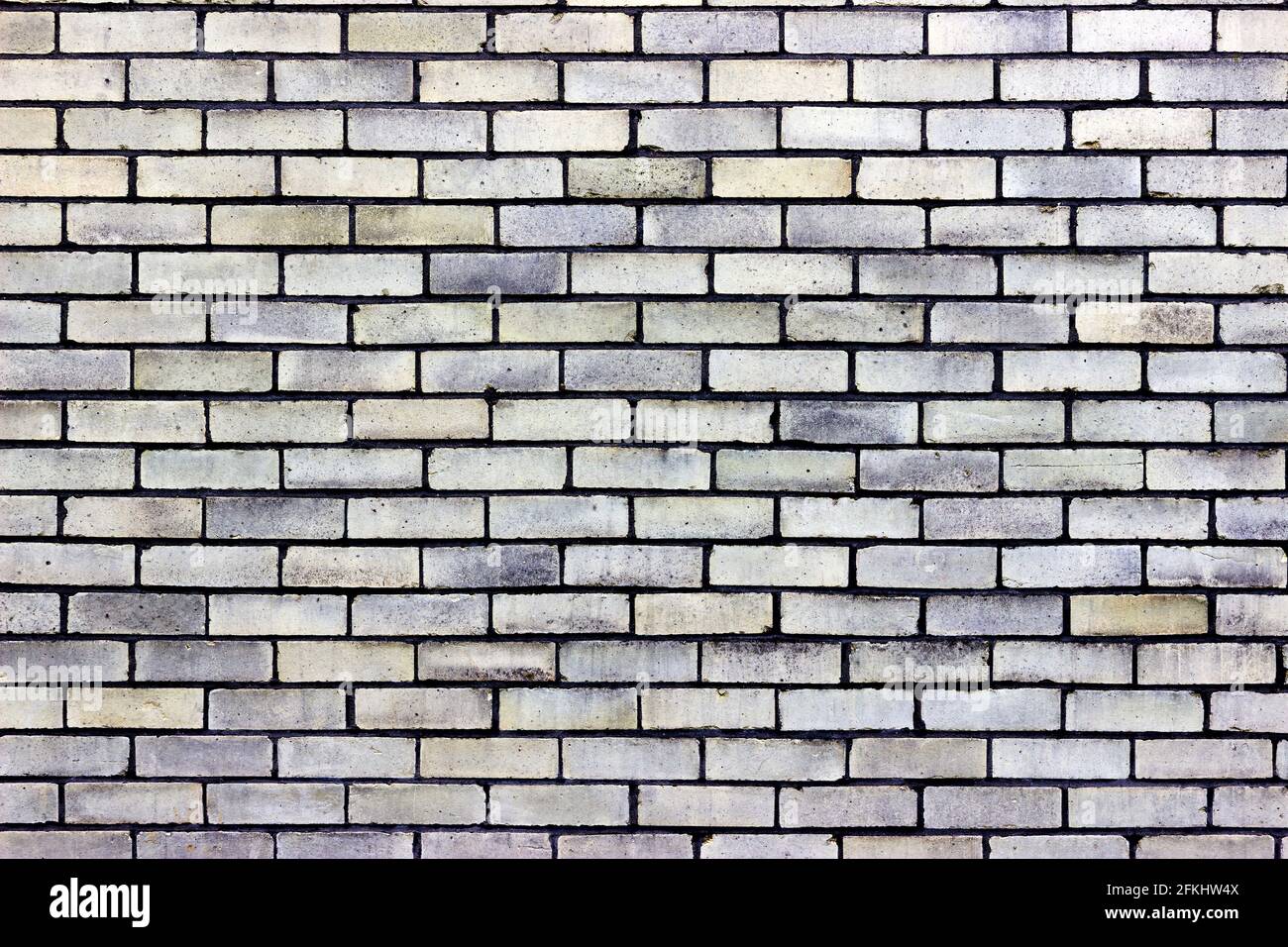 Eine hellgelbe Ziegelwand mit Blautönen Stockfoto