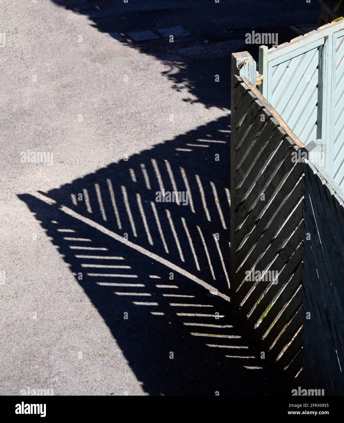 Grün bemaltes Holzgartentor und Zaun mit Schatten. Stockfoto