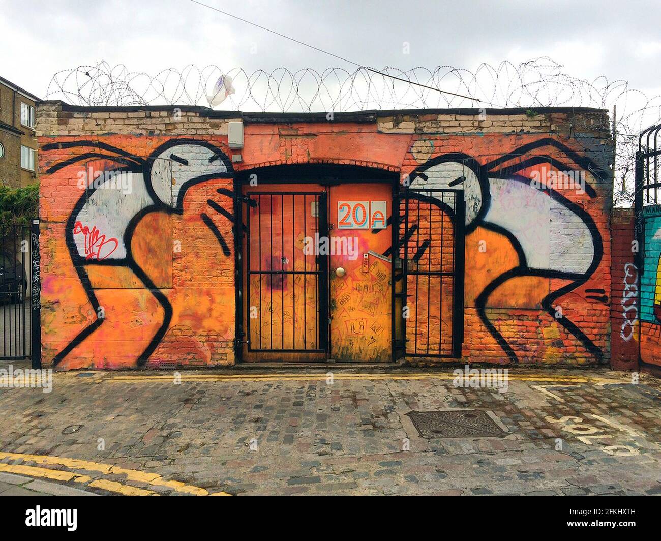 London, Großbritannien - 11. Juni 2015: Lustige Wandmalerei und Stacheldraht an einem Gebäude Stockfoto