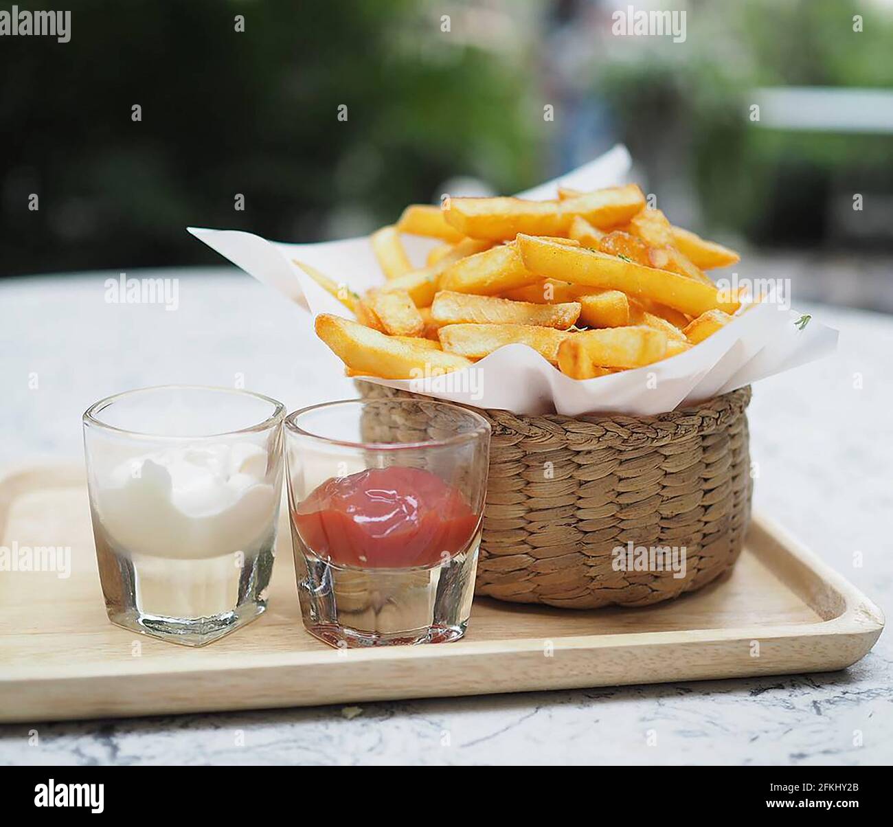 Pommes frites, Kartoffelchips Gelbe knusprige Pommes im Holzkorb, Snack lecker mit Tomatensauce und Mayonnaise auf Holztablett Stockfoto