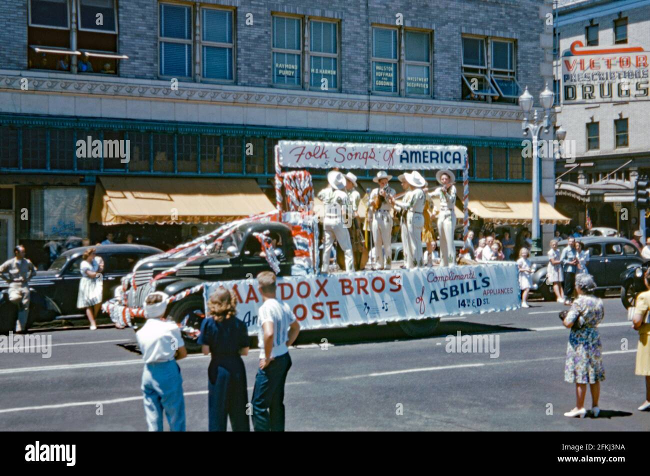 Die Maddox Brothers und Rose spielen ‘Volkslieder’ auf der Rückseite eines Pritschenwagens bei einer amerikanischen Straßenparade in den späten 1940er Jahren. Die Maddox Brothers und Rose waren bekannt als Amerikas ‘bunteste Hillbilly-Band’, die das spielte, was die Band als ‘Country Boogie’ beschrieb. Die Gruppe aus Boaz, Alabama, USA, begann in den 1930er Jahren zu spielen und bestand aus vier Brüdern zusammen mit Schwester Rose. Die Gruppe löste sich 1956 auf. Dieses Bild stammt von einem alten amerikanischen Amateur Kodak Farbtransparenz – einem Vintage-Foto aus den 1940er Jahren. Stockfoto