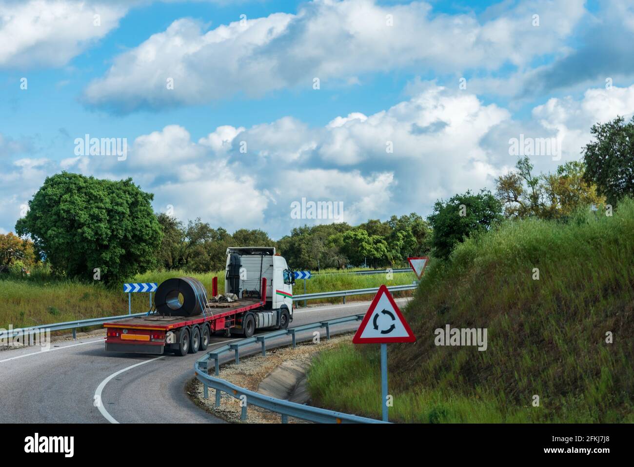 LKW, der eine Metallspule transportiert, die sicher in der Mitte des Aufliegers befestigt ist. Stockfoto