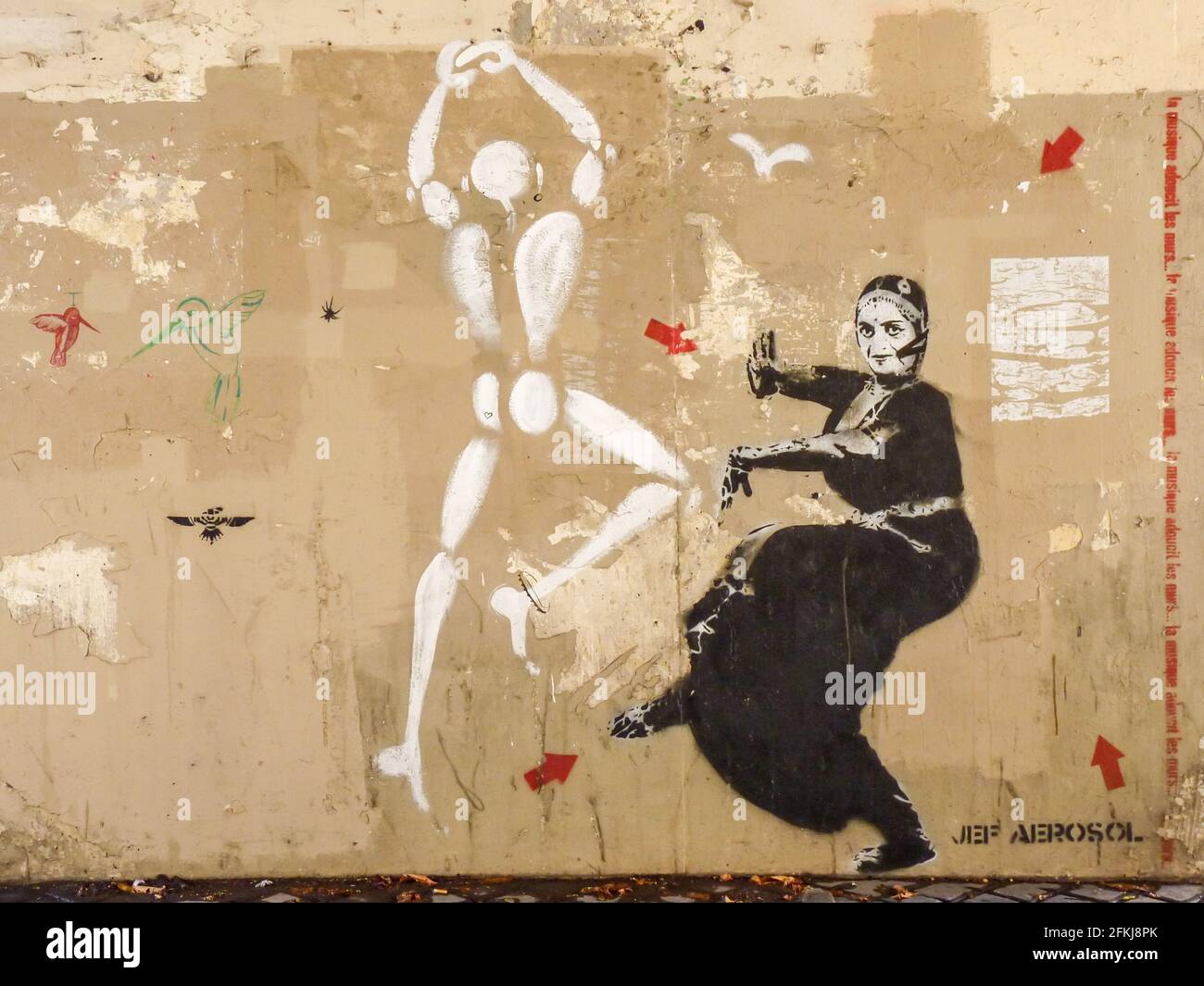 Street Art mit einer tanzenden weiblichen Figur in ethnischer Tracht in schwarz und bemalter weißer Menschenfigur. Graffiti von Jeff Aerosol, Paris. Stockfoto