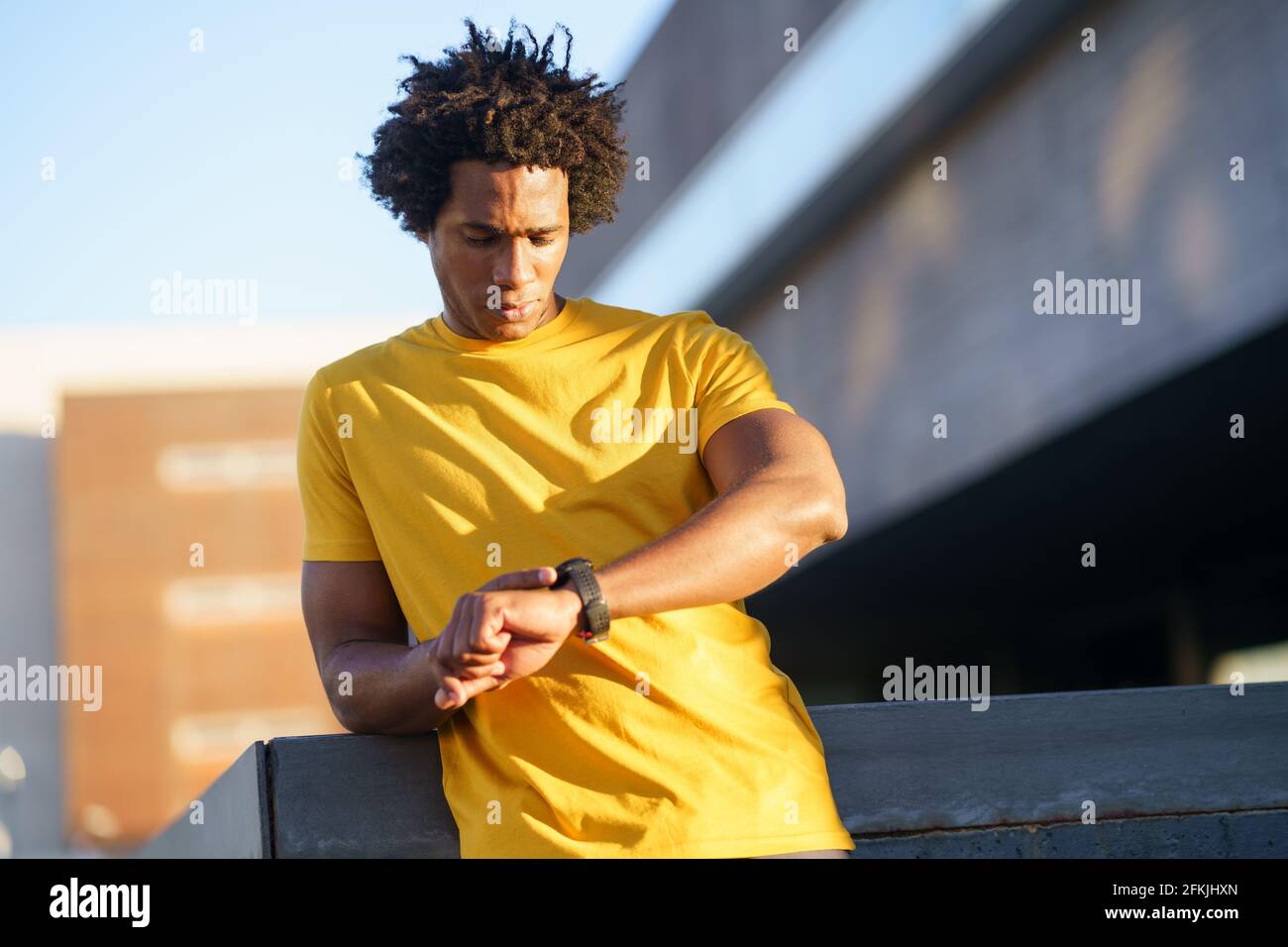 Schwarzer Mann, der seine Smartwatch konsultiert, um sich seine Trainingsdaten anzusehen. Stockfoto