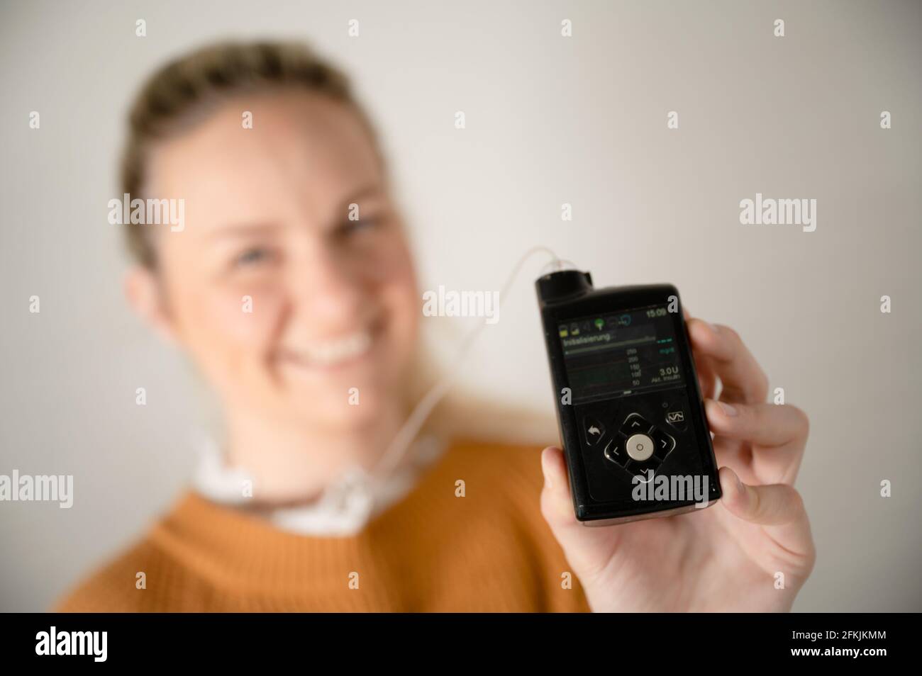 Attraktive blonde Frau hält ihre Insulinpumpe - Behandlung von Diabetes Mit Technologie Stockfoto