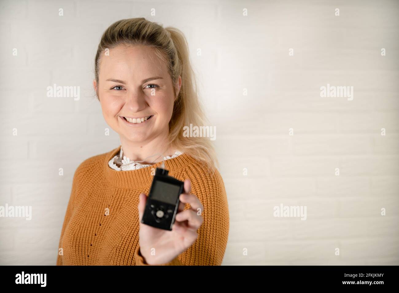 Attraktive blonde Frau hält ihre Insulinpumpe - Behandlung von Diabetes Mit Technologie Stockfoto