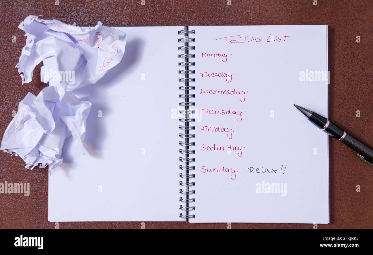 To-Do-Liste für eine Woche. Offenes Notizbuch mit schwarzer Abdeckung auf braunem Hintergrund. . Großes Textfeld Stockfoto