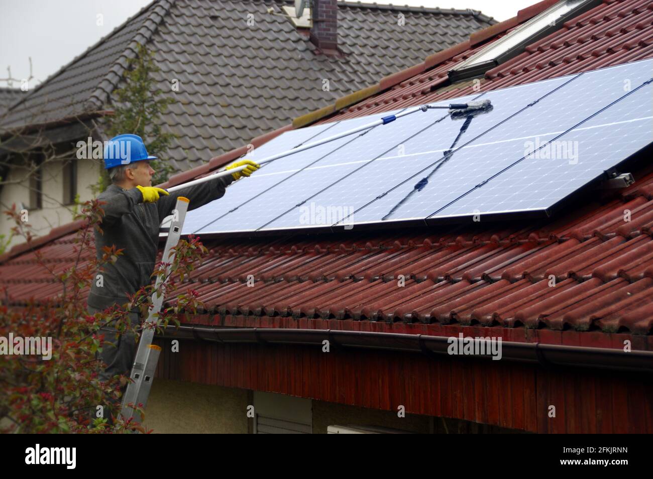 Reinigung von Solarmodulen. Ein Mann auf einer Leiter reinigt und wäscht eine Photovoltaikanlage. Stockfoto