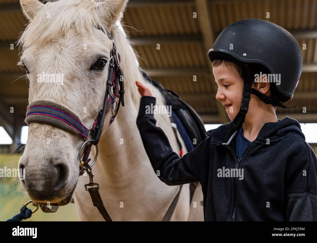 Junge mit Reithut und Pferd beim Reiten für Behinderte, Muirfield Riding Therapy, East Lothian, Schottland, Großbritannien Stockfoto