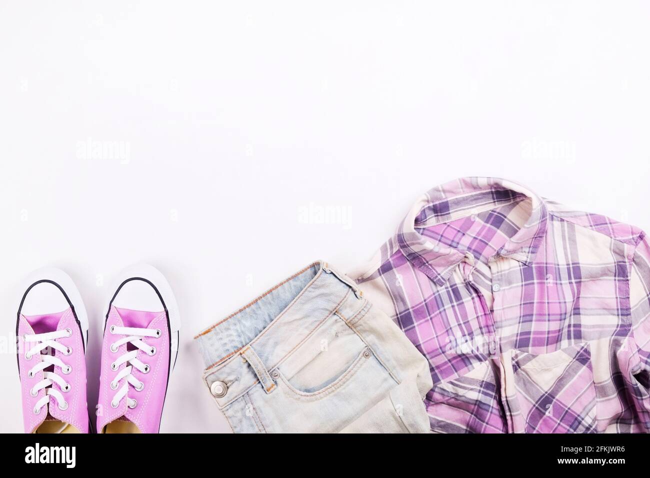 Internationaler Tagesverkauf für Damen. Frauenkleidung & Accessoires, Kollektion für den Frühling Sommer. Lila kariertes Karo-Hemd mit passenden lässigen Sneakers. Stockfoto