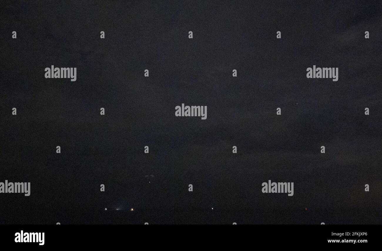 Die Raumsonde SpaceX Crew Dragon Resilience wird in der Ferne gesehen, als sie mit den NASA-Astronauten Mike Hopkins, Shannon Walker und Victor Glover und dem Astronauten der Japan Aerospace Exploration Agency (JAXA), Soichi Noguchi, an Bord im Golf von Mexiko vor der Küste von Panama City, Florida, am Sonntag, den 2. Mai 2021, landet. NASAâÂ € Â™s SpaceX Crew-1-Mission war der erste Rundflug der Besatzung der Raumsonde SpaceX Crew Dragon und Falcon 9 Rakete mit Astronauten zur Internationalen Raumstation als Teil des agencyâÂ € Â™s Commercial Crew Program. Hinweis: Dieses Bildrauschen ist das Ergebnis der Verwendung eines sehr hohen sen Stockfoto
